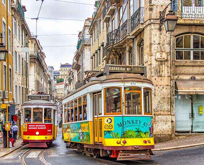 Two yellow and white trams on Lisbon street during daytime